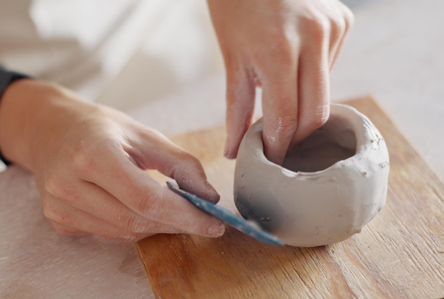 Hände formen Keramikbecher mit Werkzeug – Atelier Tonga Workshop.