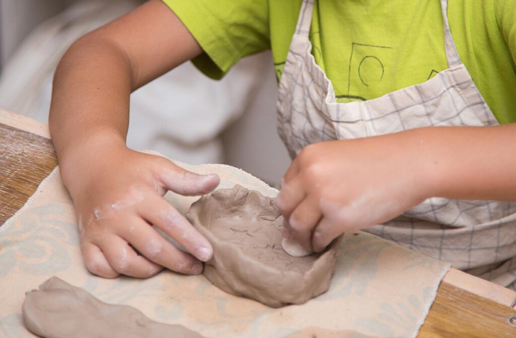 Kinder beim Modellieren von Tonfiguren im Atelier Tonga.