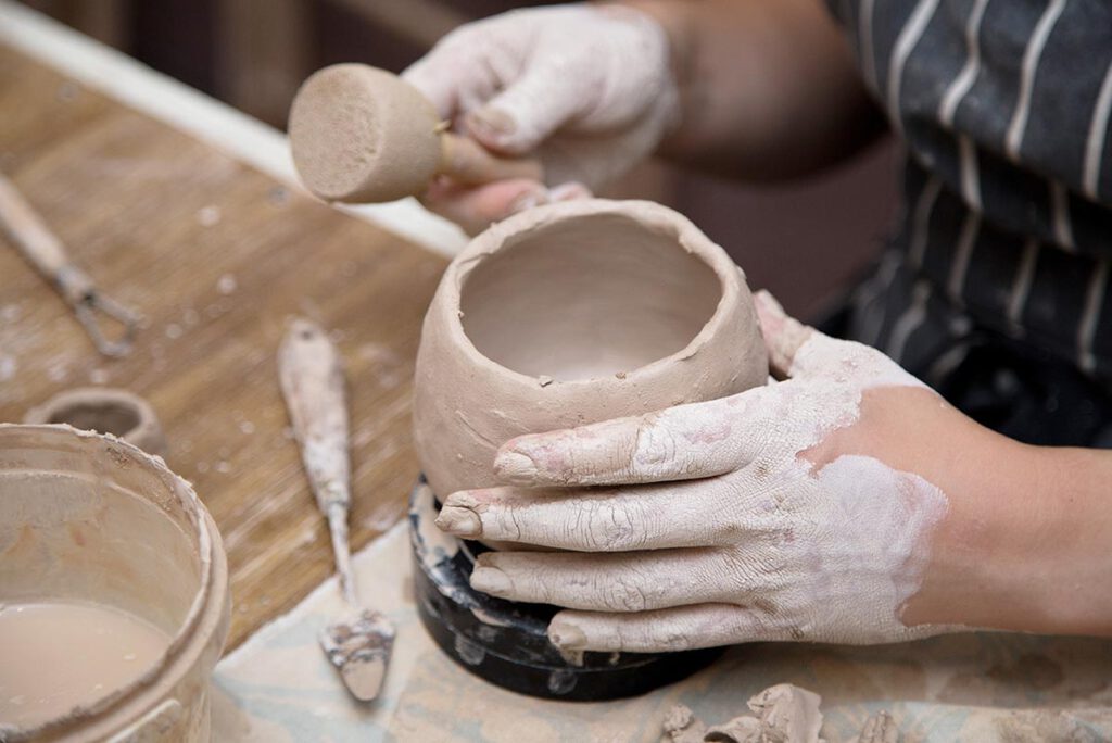 Hände formen einen Tonbecher im Workshop – Atelier Tonga München.